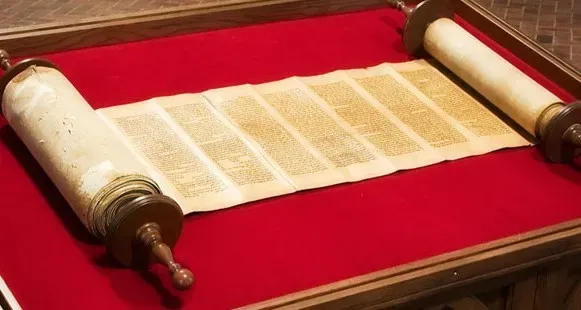An aged Hebrew Torah scroll unrolled on red velvet in a wooden display case